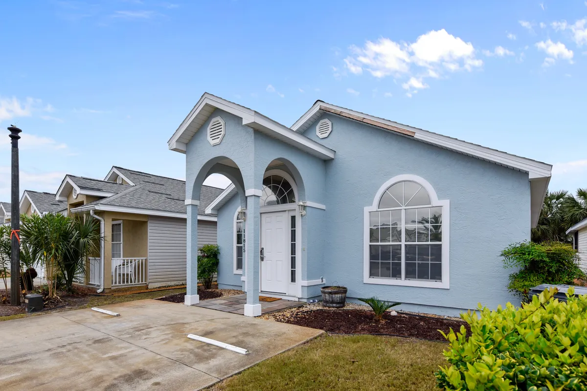 The attractive front façade of a house with an arched entryway, large windows, and a landscaped yard, suggesting a comfortable and inviting place to stay. The scene hints at family arrivals and first impressions.