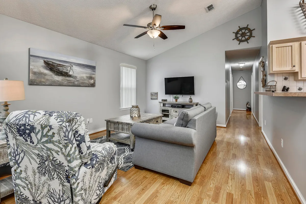 A comfortable living area with a plush sofa, decorative chair, coffee table, and TV, accented by tasteful artwork. The mood is inviting and relaxed, ideal for family movie nights, games, or unwinding after a day of activities.